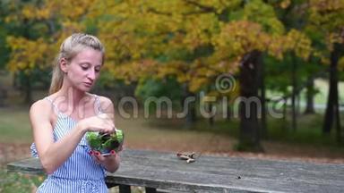 坐在公园里吃新鲜沙拉的女人。 健康素食食品